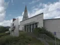 Il museo retico, con la sua architettura moderna e un'installazione artistica di un guerriero a cavallo, si erge sotto un cielo nuvoloso.