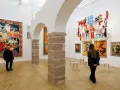 Un visitatore ammira un arazzo colorato e installazioni futuristiche al muse rovereto.