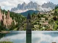 Torre sommersa nel lago di Resia, Trentino Alto Adige, con le piramidi di terra e le Dolomiti sullo sfondo.