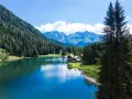 Incantevole lago alpino vicino a Madonna di Campiglio, con boschi rigogliosi, montagne maestose e un rifugio accogliente.