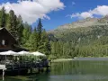 Rifugio in legno con tavoli all'aperto sul lago, circondato da boschi e montagne. Un luogo incantevole per scoprire cosa vedere a Pellizzano.