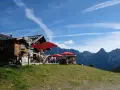 Rifugio alpino con tavoli all'aperto e vista sulle montagne, ideale per il giro delle malghe San Martino di Castrozza.