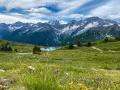 Un incantevole passo tra Lombardia e Trentino, con un lago alpino specchiato e montagne innevate sullo sfondo.