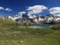 Laghi Val di Sole raggiungibili in auto: specchio d'acqua alpino con montagne innevate sullo sfondo e cielo azzurro con nuvole bianche.