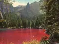 Un suggestivo lago che cambia colore, circondato da una fitta foresta di conifere e imponenti montagne.