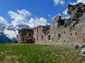 Rovine del forte Zaccarana, con montagne innevate sullo sfondo e cielo azzurro con nuvole bianche.