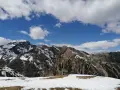 Cimon di Bolentina, un maestoso panorama montuoso con cime innevate e un cielo azzurro punteggiato di nuvole bianche.