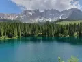 Laghi alpini in Val di Fassa, con acque cristalline che riflettono la foresta di abeti e le maestose cime dolomitiche innevate.