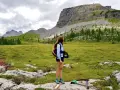 Ragazza con zaino ammira un paesaggio alpino con un imponente turrion basso.