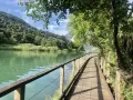 Sentiero in legno lungo il lago di Toblino, con montagne verdi sullo sfondo. Ideale per scoprire come arrivare.