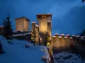 Castello innevato illuminato di notte, con alberi di Natale e luci che ricordano i mercatini di Natale di Ossana.
