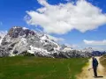 Un escursionista si ferma su un sentiero di montagna, con imponenti vette innevate sullo sfondo. Perfetti percorsi per camminare.