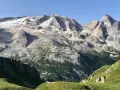 Vette innevate del Viel del Pan si stagliano maestose su un paesaggio alpino verdeggiante, con un piccolo borgo incastonato tra i boschi.