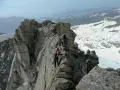 Alpinisti in cordata affrontano un crinale roccioso innevato, con la **cima Presanella** sullo sfondo.