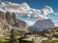 Panorami mozzafiato al Passo Gardena, con imponenti vette rocciose e un'altitudine che toglie il fiato. Case e strade si snodano tra i verdi pendii.