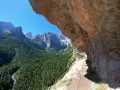 Sentieri panoramici vicino al Lago di Molveno, con un sentiero che costeggia una parete rocciosa e una vista mozzafiato sulle montagne e una cascata in lontananza.