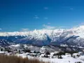 Paesaggio invernale con case innevate e montagne maestose sullo sfondo, un incantevole scenario al Passo Bondone.