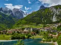 Villaggio alpino con case colorate e lago azzurro, incastonato tra montagne verdi e innevate. Ecco cosa vedere a Molveno per un panorama mozzafiato.