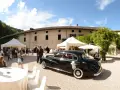 Matrimonio a Caldonazzo centro storico: auto d'epoca nera, tavoli allestiti, ospiti e un campanile sullo sfondo.