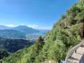 Vista panoramica dal Monte Vezzena con lago azzurro e montagne sullo sfondo. Strada con galleria scavata nella roccia.