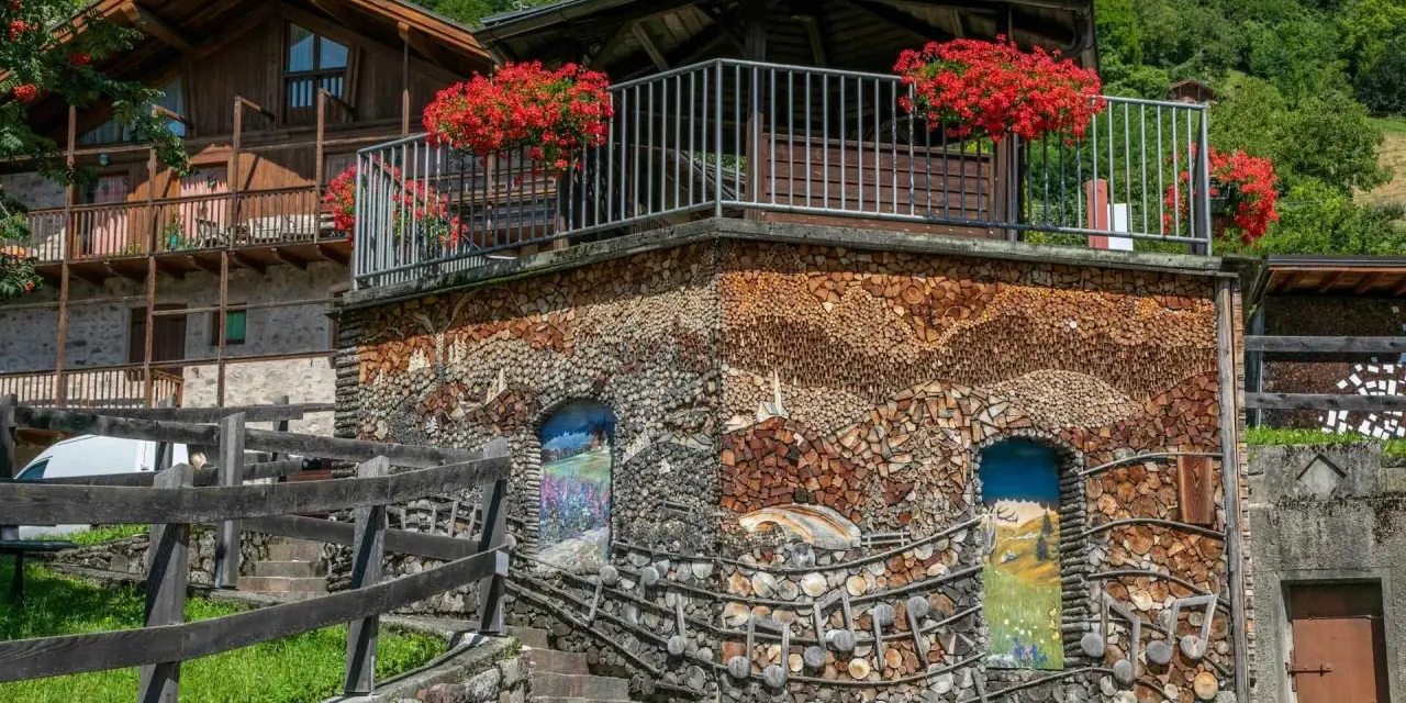 Un edificio unico in montagna, con pareti di legna e dipinti. Un vero spettacolo da vedere a Mezzano, tra natura e arte.