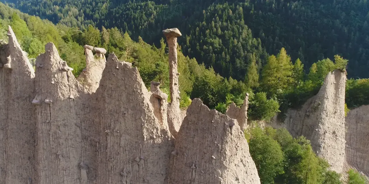 Le piramidi di terra del Val di Cembra, un paesaggio unico da scoprire, con rocce scolpite dal tempo e vegetazione rigogliosa.