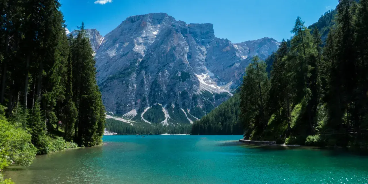 Lago di Braies, perla del tour Trentino, con montagne imponenti e acque cristalline.
