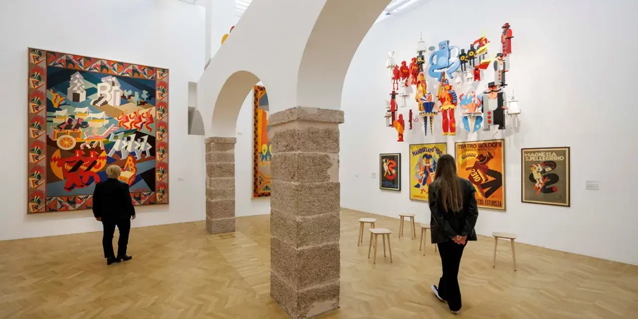 Un visitatore ammira un arazzo colorato e installazioni futuristiche al muse rovereto.