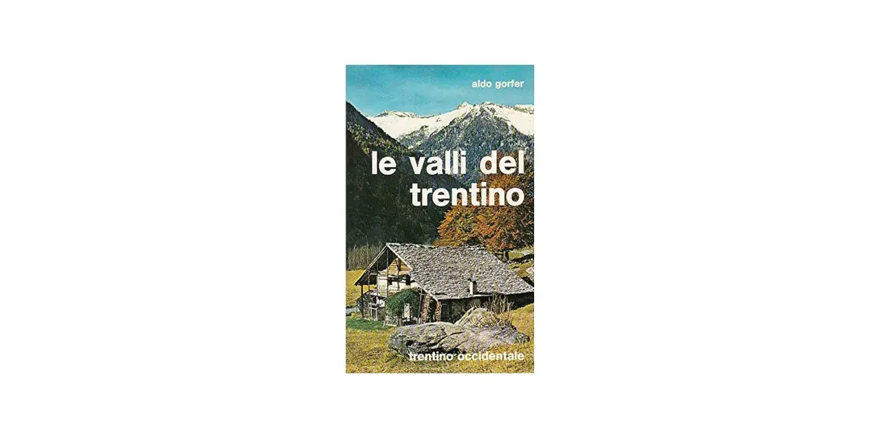 Copertina del libro "Le valli del Trentino" di Aldo Gorfer, con un casolare in pietra e tetto spiovente, montagne innevate sullo sfondo e alberi autunnali.