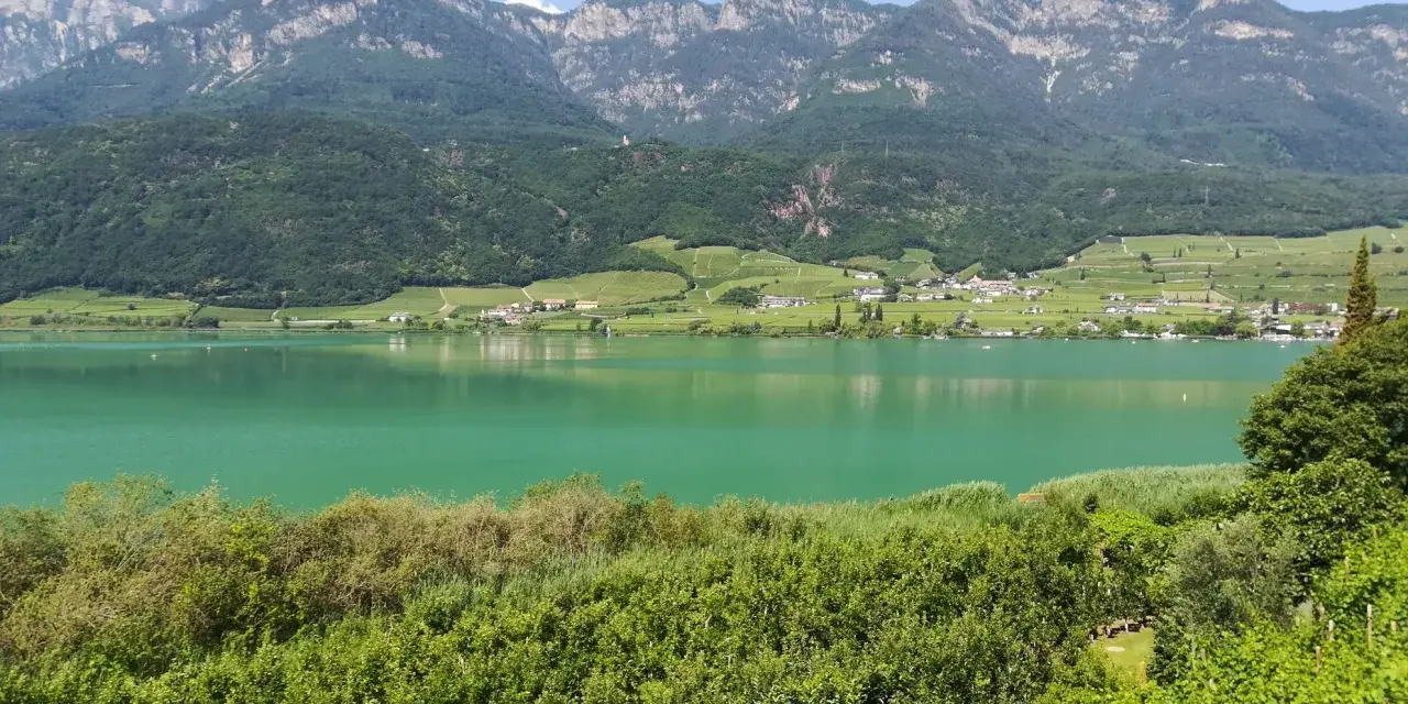 Lago di Caldaro, un gioiello verde smeraldo incastonato tra vigneti e montagne. Cosa vedere a Ronzone? Questo paesaggio mozzafiato è solo un assaggio.