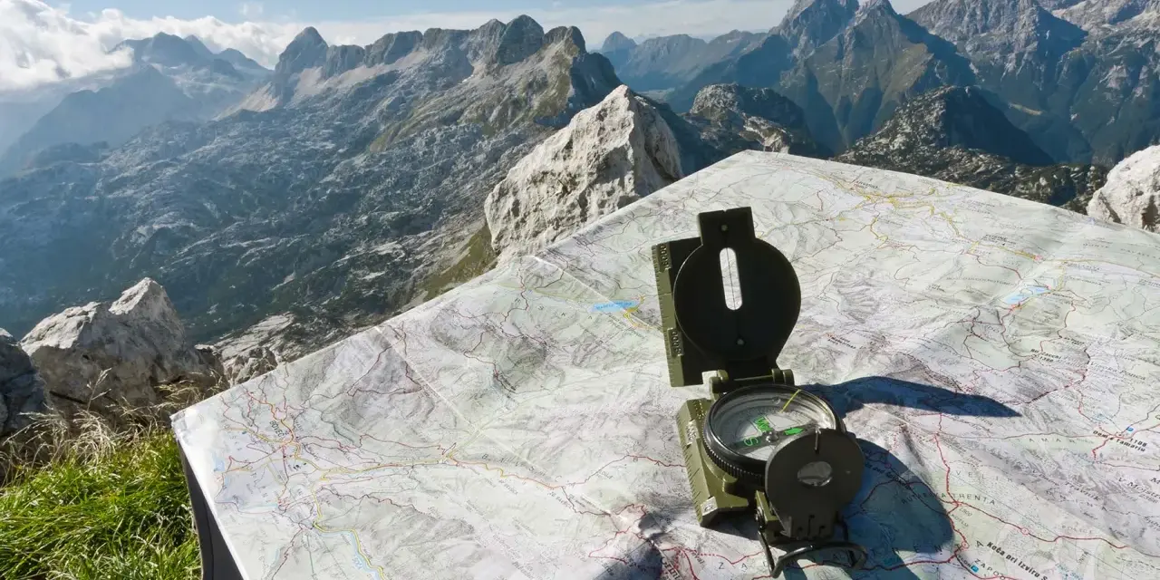 Bussola e mappa del passo della Fricca, con un panorama mozzafiato sulle montagne.