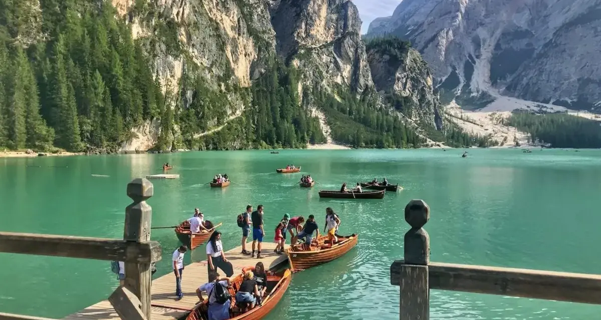 Gente in barca sul lago di Braies, dove si trova questo gioiello alpino. Montagne imponenti e acque turchesi.