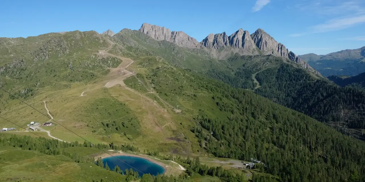 Panorami mozzafiato per passeggiate facili vicino a Trento. Un lago alpino azzurro e sentieri tra prati e boschi.