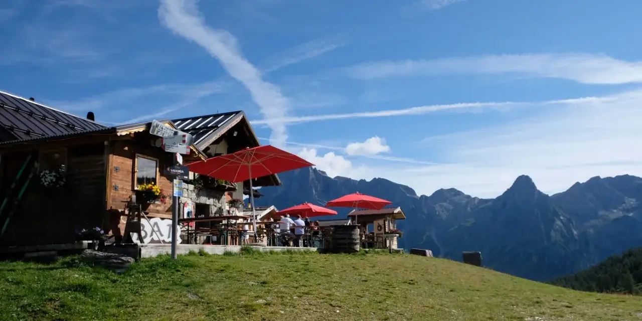 Rifugio alpino con tavoli all'aperto e vista sulle montagne, ideale per il giro delle malghe San Martino di Castrozza.