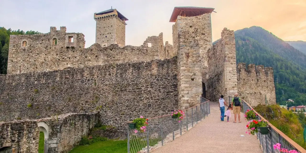 Castello di Stenico, uno dei tanti paesi da visitare vicino Dimaro, con una famiglia che passeggia sul ponte fiorito.