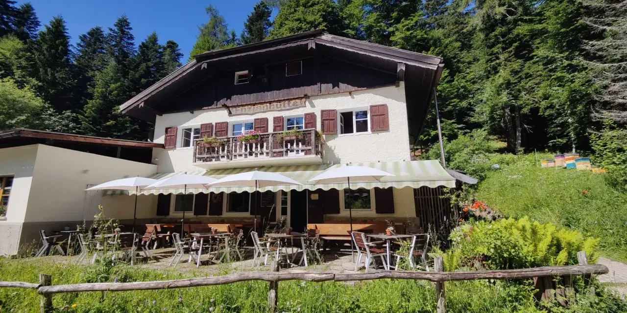 Rifugio alpino con tavoli all'aperto, ideale per rilassarsi dopo le ronzone passeggiate nel bosco.