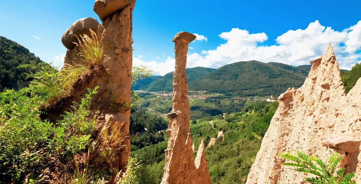 Le Piramidi di Segonzano, un paesaggio unico da esplorare. Le formazioni rocciose scolpite dal tempo dominano la valle verdeggiante.