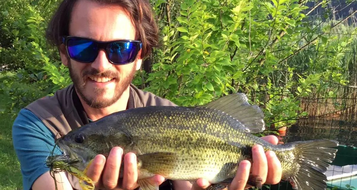 Felice pescatore con un grosso pesce appena pescato al lago di Levico.