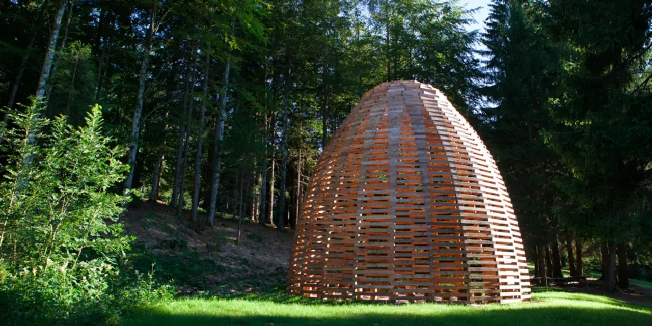 Struttura artistica in legno nel bosco, un'installazione di Arte Sella a Borgo Valsugana.
