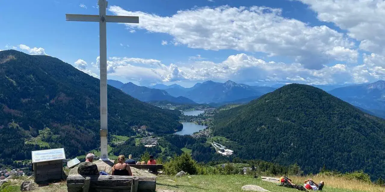 Croce in cima a una collina con vista panoramica su laghi e montagne, nei pressi di Bedollo, Trento.