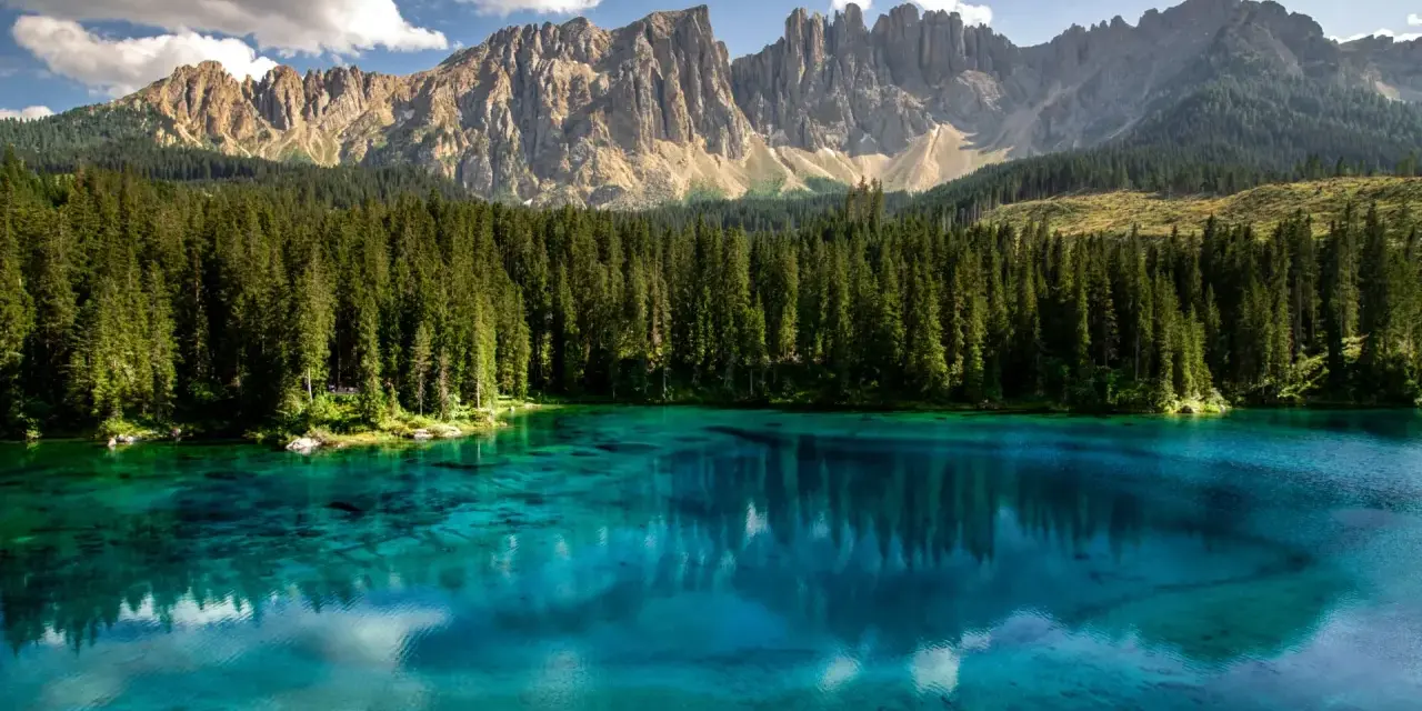 Lago di Carezza, un gioiello tra i boschi e le Dolomiti del Trentino, dove andare per un'immersione nella natura.