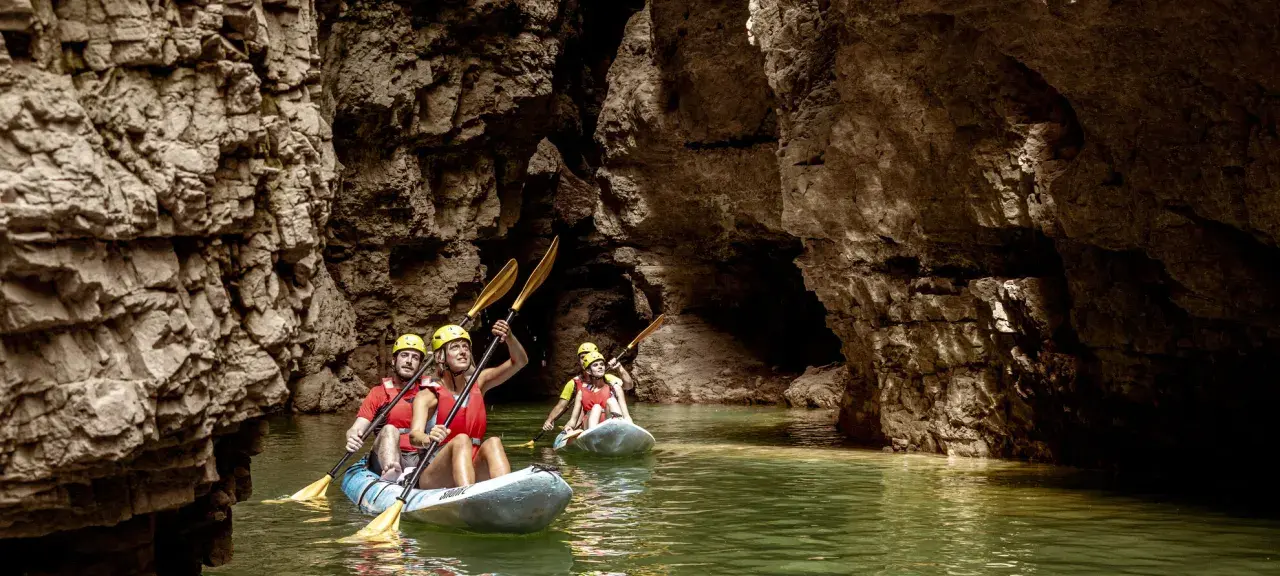 Kayakisti esplorano il suggestivo lago di Santa Giustina canyon, tra pareti rocciose imponenti e acque verdi.