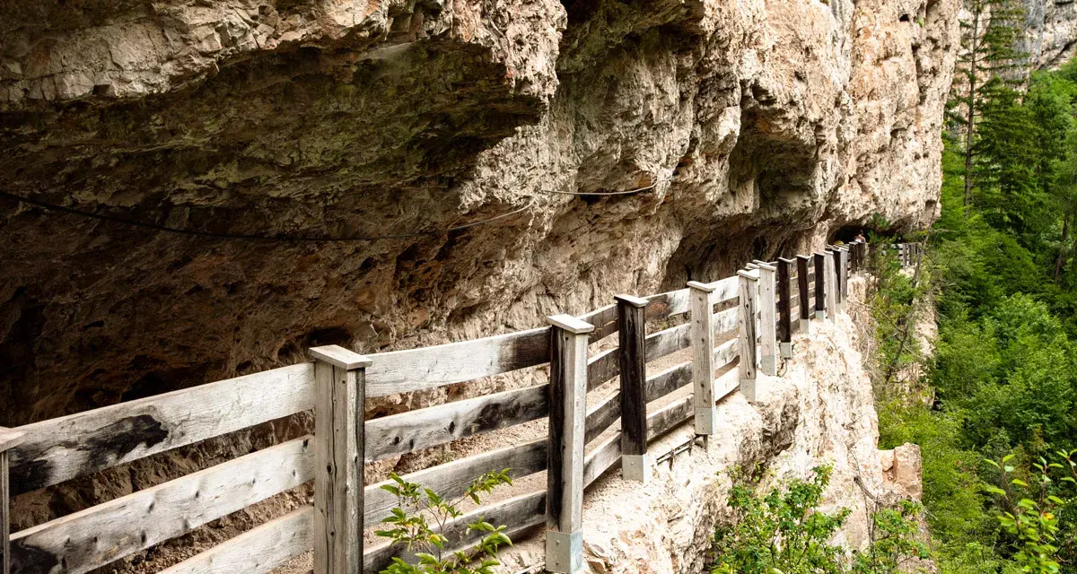 Sentiero panoramico con staccionata in legno lungo la roccia, vicino a Sanzeno San Romedio.