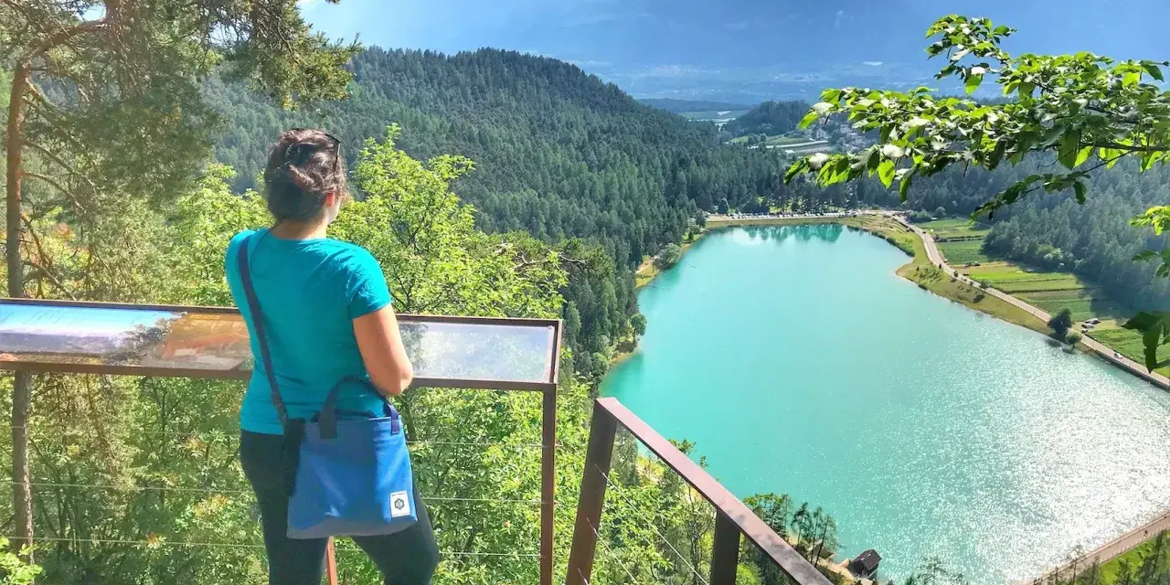 Donna ammira il lago turchese durante una passeggiata della merlonga, con montagne sullo sfondo.