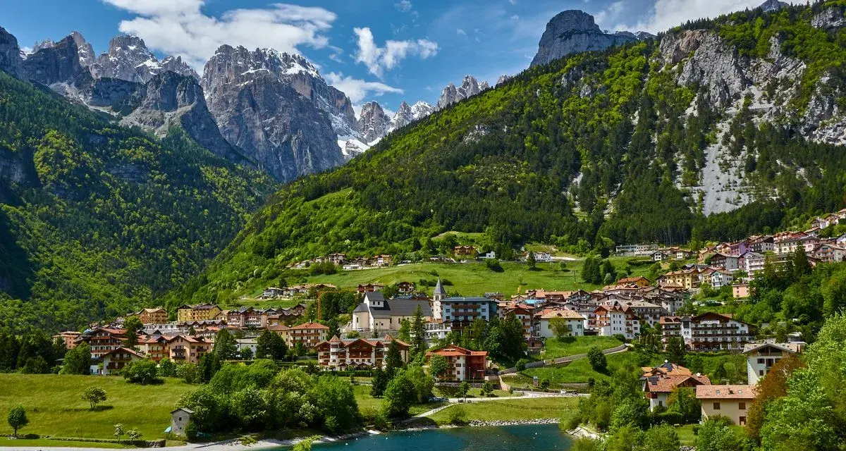 Villaggio alpino con case colorate e lago azzurro, incastonato tra montagne verdi e innevate. Ecco cosa vedere a Molveno per un panorama mozzafiato.