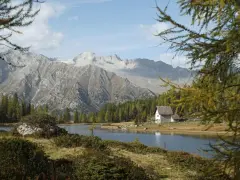 Un rifugio solitario si specchia nei laghi di San Giuliano, circondato da boschi e imponenti montagne.