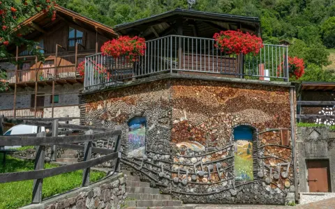 Un edificio unico in montagna, con pareti di legna e dipinti. Un vero spettacolo da vedere a Mezzano, tra natura e arte.