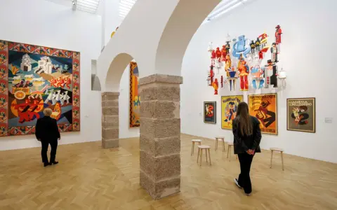 Un visitatore ammira un arazzo colorato e installazioni futuristiche al muse rovereto.