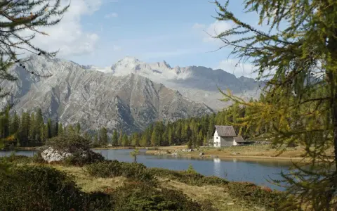Un rifugio solitario si specchia nei laghi di San Giuliano, circondato da boschi e imponenti montagne.