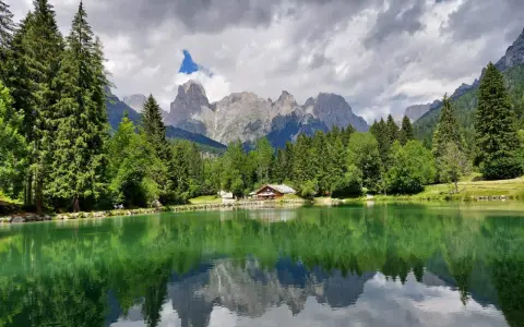 Riflessi alpini sul lago di Passo Cereda. Montagne imponenti e boschi verdi incorniciano un tranquillo specchio d'acqua.